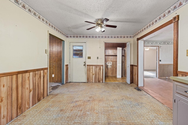 18 County Road 252nd Rd, Glen, MS 38846 - empty room with a ceiling fan, a wainscoted wall, a textured ceiling, and wooden walls