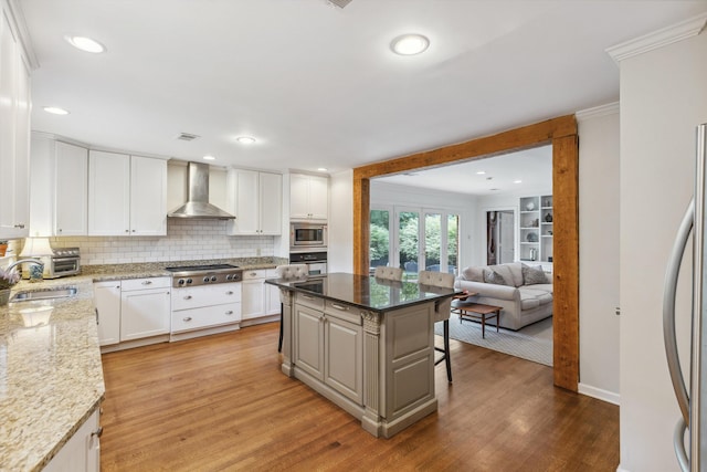 215 Belhaven St, Memphis, TN 38117 - kitchen with wall chimney range hood, appliances with stainless steel finishes, a breakfast bar, ornamental molding, and decorative backsplash