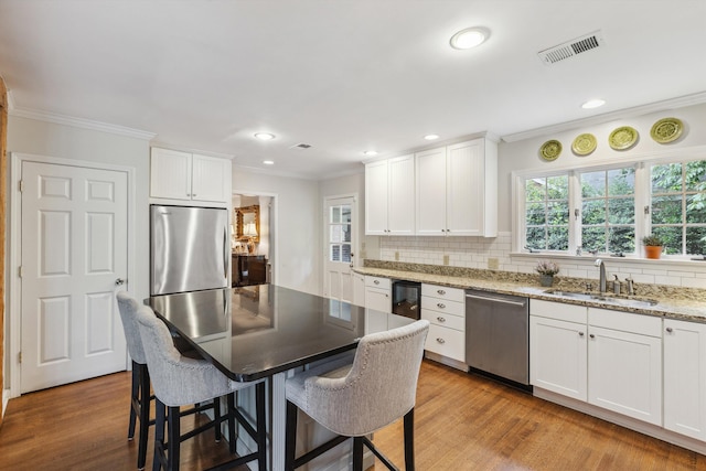215 Belhaven St, Memphis, TN 38117 - kitchen featuring appliances with stainless steel finishes, backsplash, a breakfast bar, light wood-type flooring, and ornamental molding