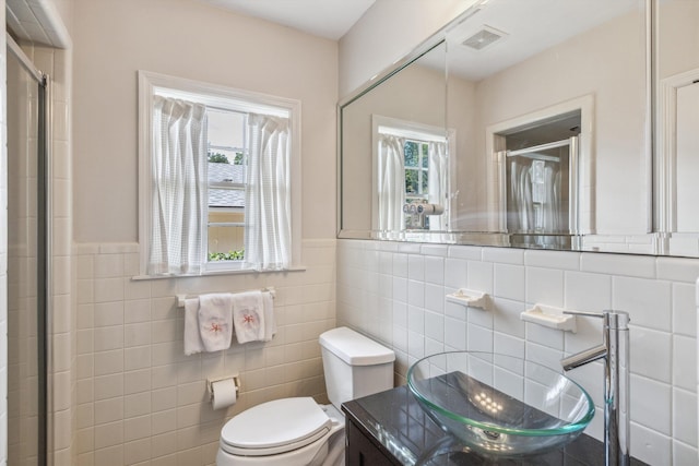 215 Belhaven St, Memphis, TN 38117 - full bathroom featuring a stall shower, tile walls, vanity, healthy amount of natural light, and a wainscoted wall