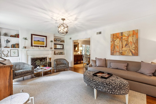 215 Belhaven St, Memphis, TN 38117 - living area featuring a premium fireplace, wood finished floors, a chandelier, crown molding, and built in features