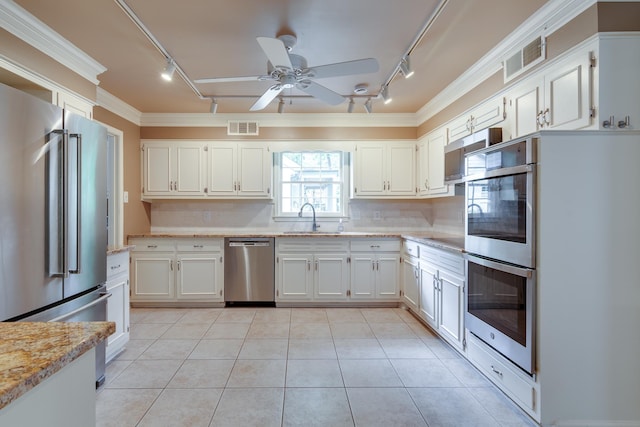 2030 Quail Creek Cv, Memphis, TN 38119 - kitchen with track lighting, appliances with stainless steel finishes, a ceiling fan, backsplash, and crown molding