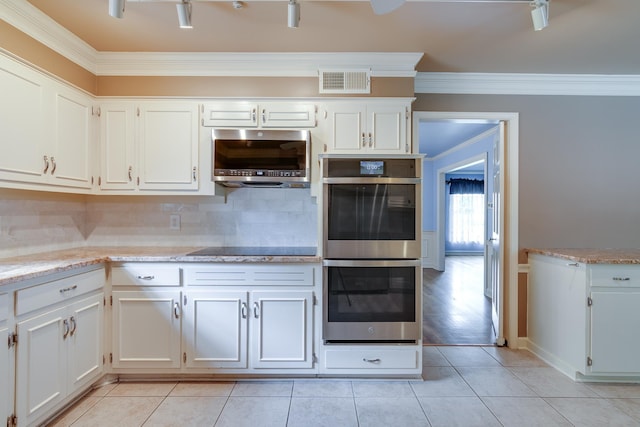 2030 Quail Creek Cv, Memphis, TN 38119 - kitchen featuring appliances with stainless steel finishes, ornamental molding, light tile patterned floors, decorative backsplash, and white cabinetry