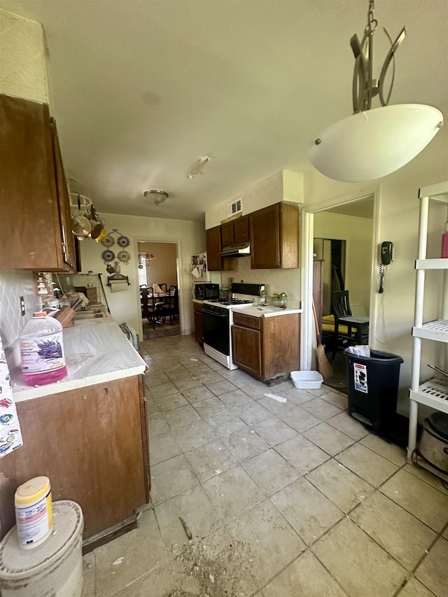 1407 Worthington St, Memphis, TN 38114 - kitchen featuring white range with gas stovetop, light countertops, under cabinet range hood, and black microwave