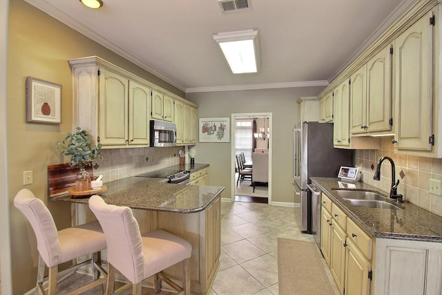 774 Wellington Way Cv, Collierville, TN 38017 - kitchen with appliances with stainless steel finishes, a peninsula, decorative backsplash, a kitchen bar, and cream cabinets