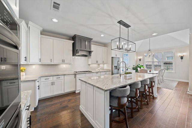 4741 Carousel Ln, Collierville, TN 38017 - kitchen featuring stainless steel appliances, a chandelier, a kitchen breakfast bar, white cabinetry, and backsplash