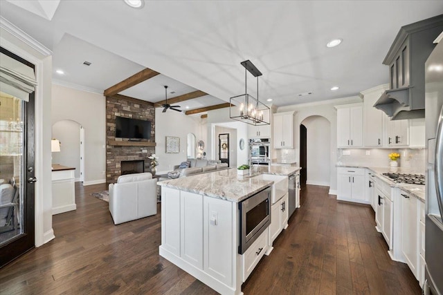 4741 Carousel Ln, Collierville, TN 38017 - kitchen featuring arched walkways, stainless steel appliances, a ceiling fan, a large fireplace, and open floor plan