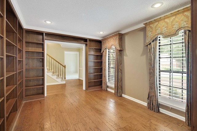 460 Jason Dr, Memphis, TN 38120 - unfurnished room featuring a textured ceiling, crown molding, stairs, light wood-style floors, and built in shelves