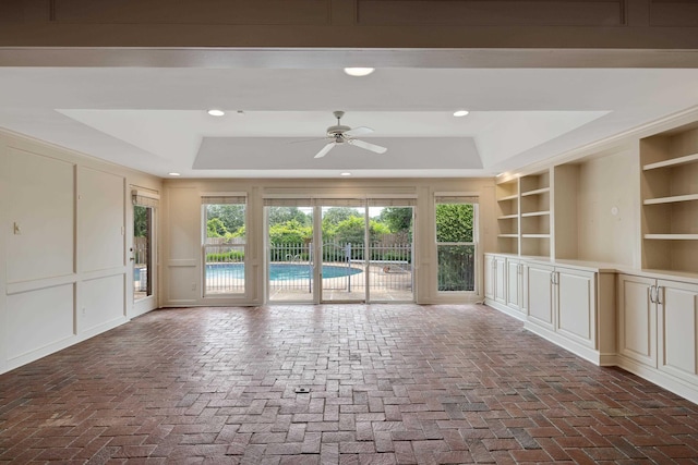 460 Jason Dr, Memphis, TN 38120 - unfurnished living room with a tray ceiling, a ceiling fan, brick floors, a decorative wall, and recessed lighting