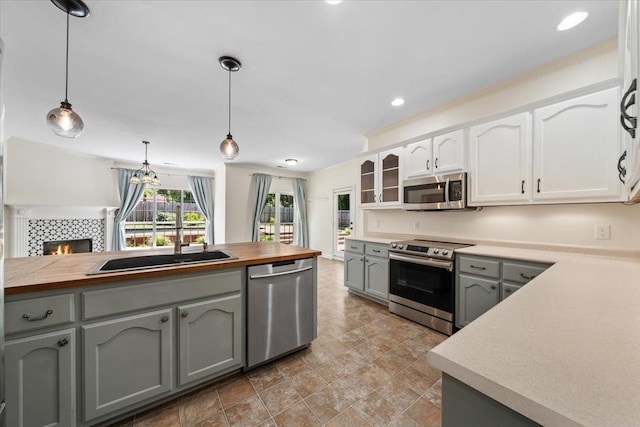 3760 Broadway Rd, Bartlett, TN 38135 - kitchen featuring stainless steel appliances, a tile fireplace, butcher block counters, decorative light fixtures, and gray cabinetry