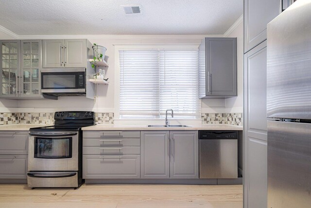 569 Lundee Pl, Memphis, TN 38111 - kitchen with stainless steel appliances, gray cabinets, ornamental molding, decorative backsplash, and light countertops