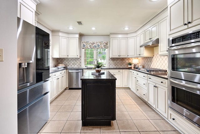 3846 Mimosa Ave, Memphis, TN 38111 - kitchen featuring appliances with stainless steel finishes, under cabinet range hood, decorative backsplash, a kitchen island, and light tile patterned floors