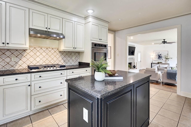 3846 Mimosa Ave, Memphis, TN 38111 - kitchen with under cabinet range hood, light tile patterned floors, stainless steel appliances, tasteful backsplash, and a center island