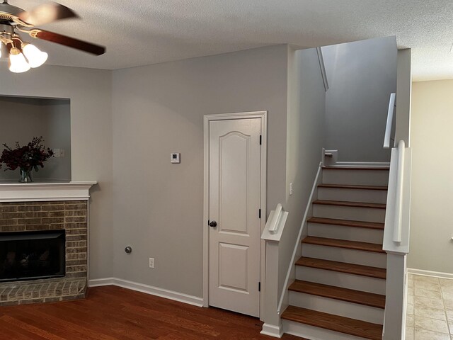 1182 Collierville-Arlington Rd, Collierville, TN 38017 - unfurnished living room featuring ceiling fan, a textured ceiling, stairway, wood finished floors, and a brick fireplace