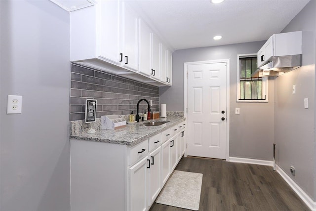 518 Jenson Rd, Memphis, TN 38109 - kitchen featuring under cabinet range hood, dark wood finished floors, decorative backsplash, light stone countertops, and white cabinets