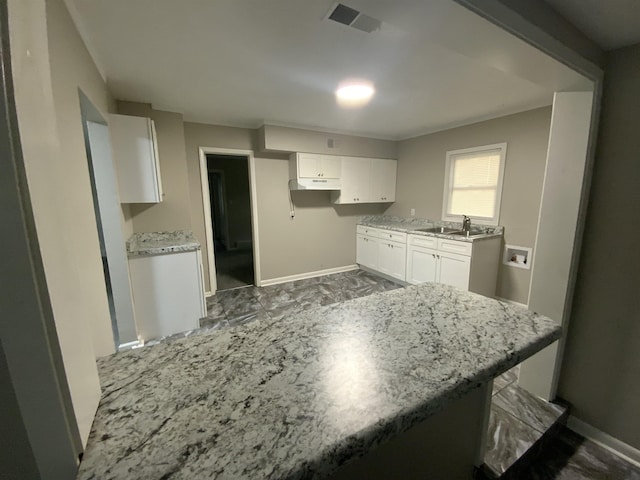 3560 Steele St, Memphis, TN 38127 - kitchen with white cabinets, under cabinet range hood, and light stone counters