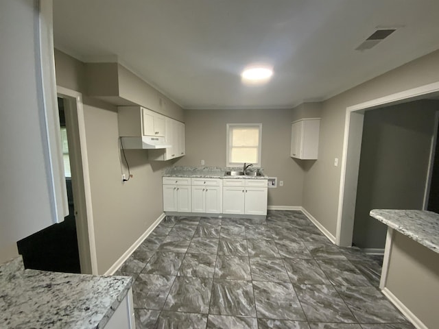 3560 Steele St, Memphis, TN 38127 - kitchen with under cabinet range hood, white cabinetry, light stone counters, and dark marble finish flooring