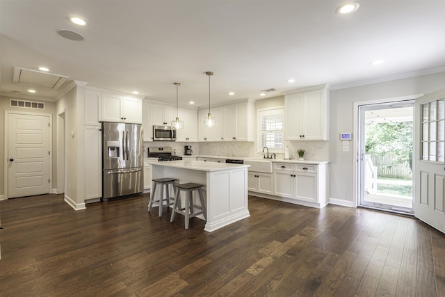 3613 Charleswood Ave, Memphis, TN 38122 - kitchen featuring appliances with stainless steel finishes, crown molding, dark wood-style floors, light countertops, and white cabinetry