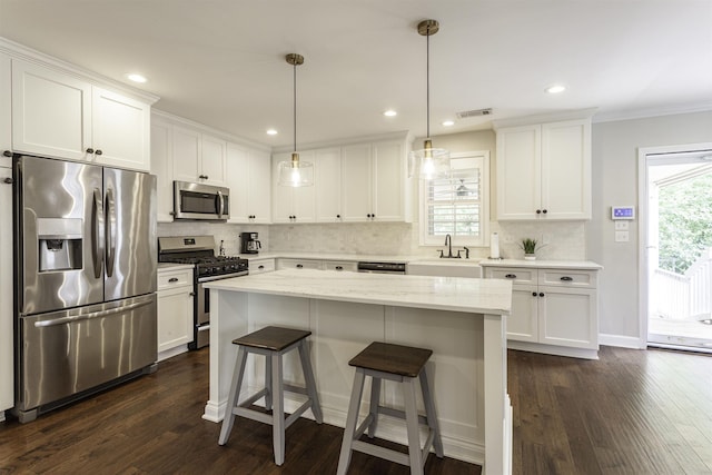 3613 Charleswood Ave, Memphis, TN 38122 - kitchen with appliances with stainless steel finishes, dark wood-style floors, tasteful backsplash, white cabinetry, and ornamental molding