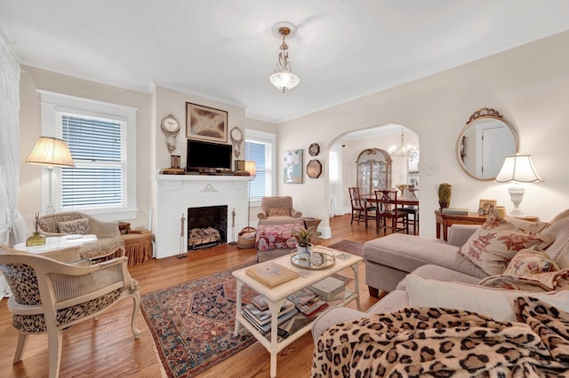 560 S Greer St, Memphis, TN 38111 - living room with arched walkways, wood finished floors, crown molding, a brick fireplace, and a chandelier