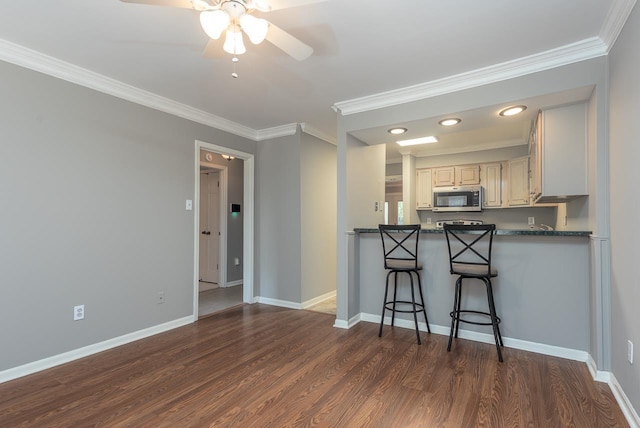 6942 Amberly Rd Unit 6942, Memphis, TN 38119 - kitchen featuring stainless steel microwave, crown molding, a ceiling fan, dark wood-type flooring, and a kitchen breakfast bar