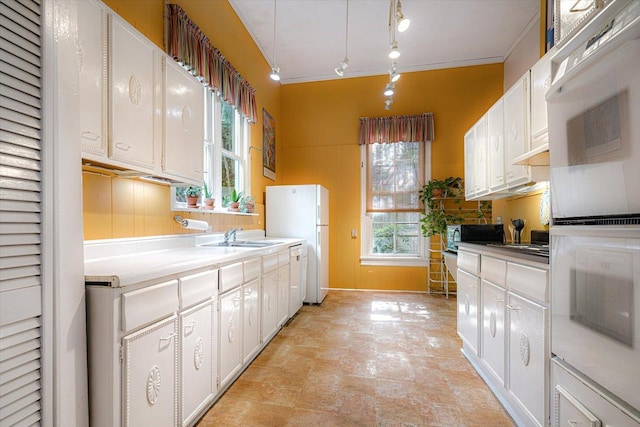 1785 Glenwood Pl, Memphis, TN 38104 - kitchen featuring white appliances, healthy amount of natural light, white cabinetry, track lighting, and crown molding