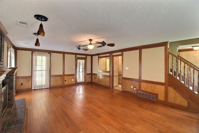 1150 Forest Wood Cv E, Collierville, TN 38017 - unfurnished living room featuring a wainscoted wall, a textured ceiling, stairway, wood-type flooring, and a fireplace