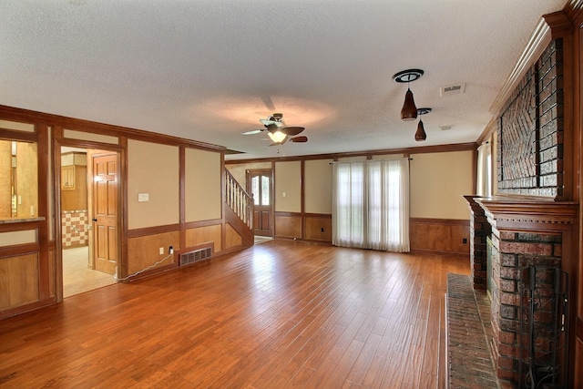 1150 Forest Wood Cv E, Collierville, TN 38017 - unfurnished living room featuring a textured ceiling, crown molding, wainscoting, a ceiling fan, and stairs
