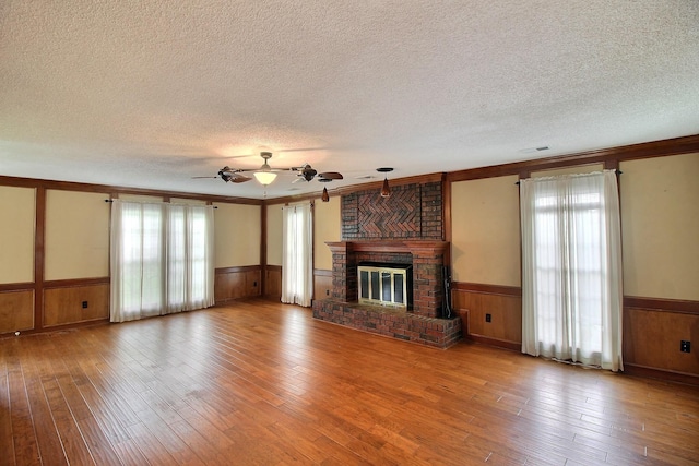 1150 Forest Wood Cv E, Collierville, TN 38017 - unfurnished living room featuring a wainscoted wall, a textured ceiling, plenty of natural light, hardwood / wood-style floors, and a fireplace