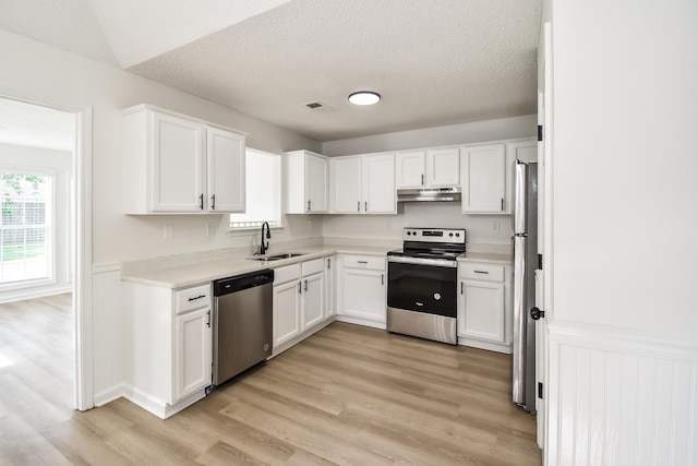 7881 Collins Wood Cv, Memphis, TN 38125 - kitchen featuring stainless steel appliances, under cabinet range hood, healthy amount of natural light, white cabinetry, and a textured ceiling