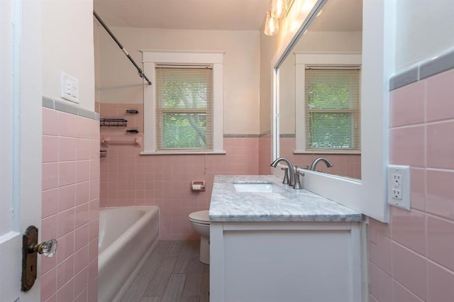 1622 Tutwiler Ave, Memphis, TN 38107 - bathroom featuring tile walls, vanity, a wainscoted wall, and bathing tub / shower combination