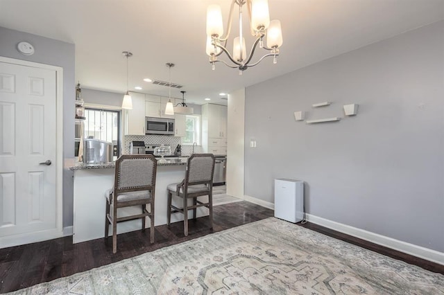 1622 Tutwiler Ave, Memphis, TN 38107 - kitchen featuring stainless steel microwave, white cabinets, decorative backsplash, dark wood-style floors, and light stone countertops