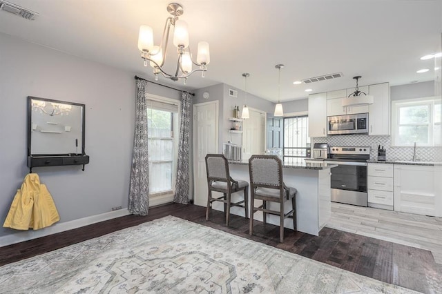 1622 Tutwiler Ave, Memphis, TN 38107 - kitchen with appliances with stainless steel finishes, white cabinets, light wood-type flooring, a chandelier, and recessed lighting