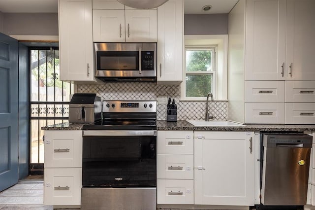 1622 Tutwiler Ave, Memphis, TN 38107 - kitchen with stainless steel appliances, decorative backsplash, white cabinetry, dark stone counters, and light wood finished floors