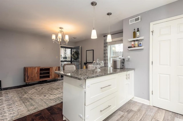 1622 Tutwiler Ave, Memphis, TN 38107 - kitchen featuring a peninsula, light wood finished floors, dark stone countertops, white cabinets, and a chandelier