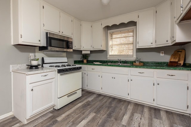 3806 Bluff Rd, Hernando, MS 38632 - kitchen with white gas stove, stainless steel microwave, white cabinets, and dark wood-style floors