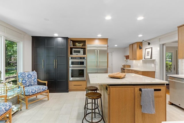 9240 Riveredge Dr, Memphis, TN 38018 - kitchen with a kitchen island, built in appliances, open shelves, light stone countertops, and a kitchen breakfast bar