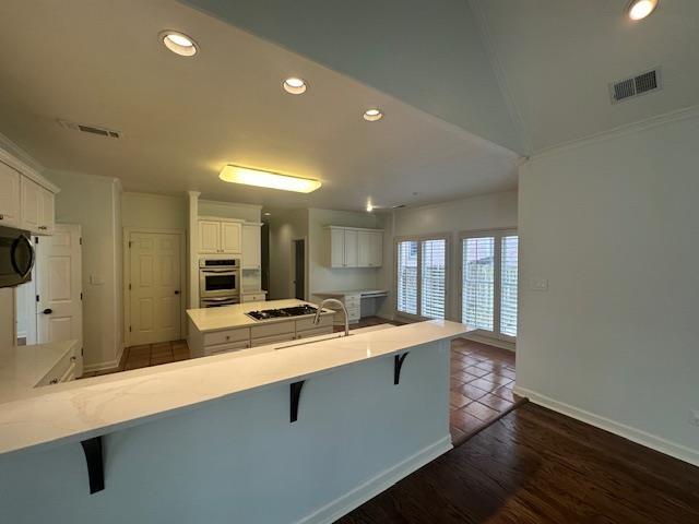 6425 Lebarrett Cv, Memphis, TN 38120 - kitchen with appliances with stainless steel finishes, recessed lighting, a peninsula, a kitchen breakfast bar, and dark wood-type flooring