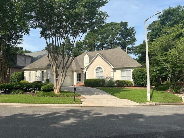 6425 Lebarrett Cv, Memphis, TN 38120 - view of front of house with an attached garage, concrete driveway, stucco siding, and a front yard