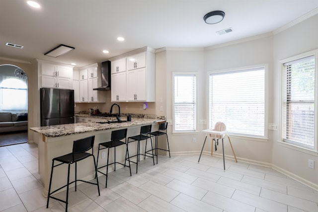 8510 Wolf Trace Ln, Bartlett, TN 38133 - kitchen with freestanding refrigerator, wall chimney range hood, a peninsula, a breakfast bar, and light stone countertops