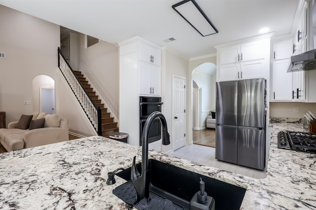 8510 Wolf Trace Ln, Bartlett, TN 38133 - kitchen with freestanding refrigerator, arched walkways, light stone countertops, black gas stovetop, and white cabinets