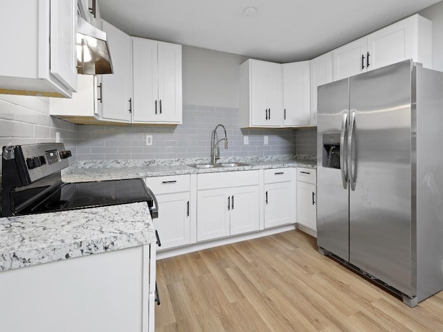 1438 Silver St, Memphis, TN 38106 - kitchen with appliances with stainless steel finishes, under cabinet range hood, light wood finished floors, and white cabinets