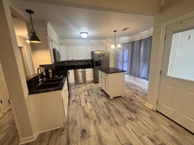 8894 Lake Edge Cv, Memphis, TN 38016 - kitchen with stainless steel appliances, dark countertops, light wood finished floors, white cabinets, and crown molding