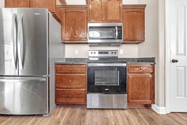 6836 Lagrange Grove Dr, Cordova, TN 38018 - kitchen with stainless steel appliances, light wood-style floors, dark stone countertops, and brown cabinetry