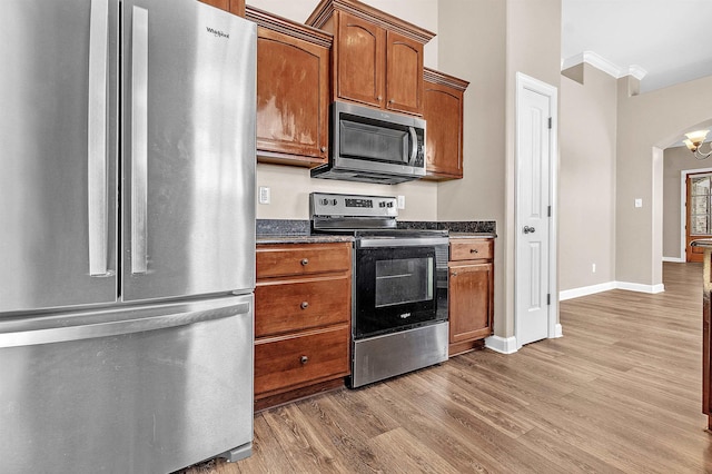 6836 Lagrange Grove Dr, Cordova, TN 38018 - kitchen featuring appliances with stainless steel finishes, light wood-style floors, crown molding, arched walkways, and brown cabinets
