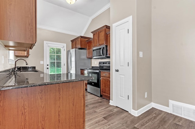 6836 Lagrange Grove Dr, Cordova, TN 38018 - kitchen featuring appliances with stainless steel finishes, crown molding, lofted ceiling, light wood finished floors, and dark stone countertops