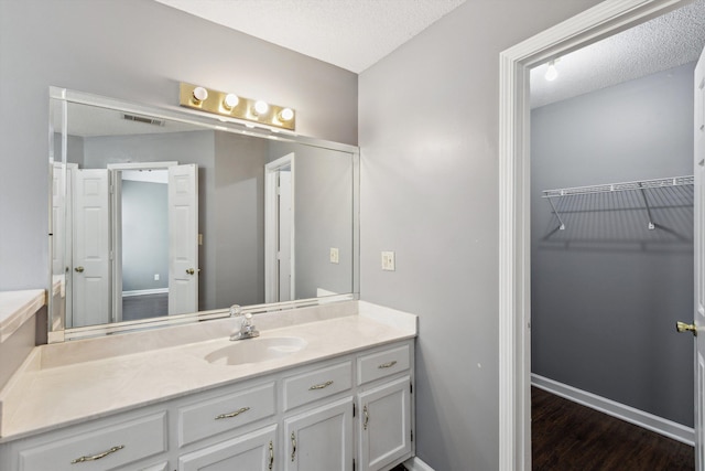 2766 Fletcher View Dr, Memphis, TN 38016 - bathroom with vanity, wood finished floors, a walk in closet, and a textured ceiling