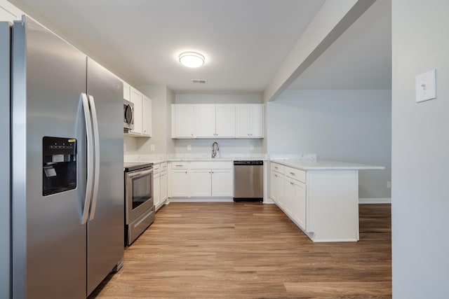 4825 Verne Rd, Memphis, TN 38117 - kitchen featuring appliances with stainless steel finishes, a peninsula, white cabinets, and light wood finished floors