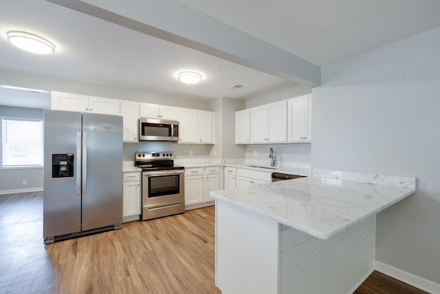 4825 Verne Rd, Memphis, TN 38117 - kitchen featuring appliances with stainless steel finishes, a peninsula, light wood-style floors, white cabinets, and light stone countertops