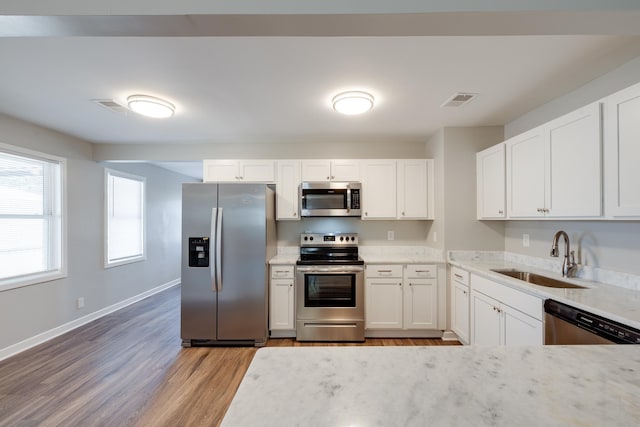 4825 Verne Rd, Memphis, TN 38117 - kitchen featuring appliances with stainless steel finishes, wood finished floors, white cabinets, and light stone countertops
